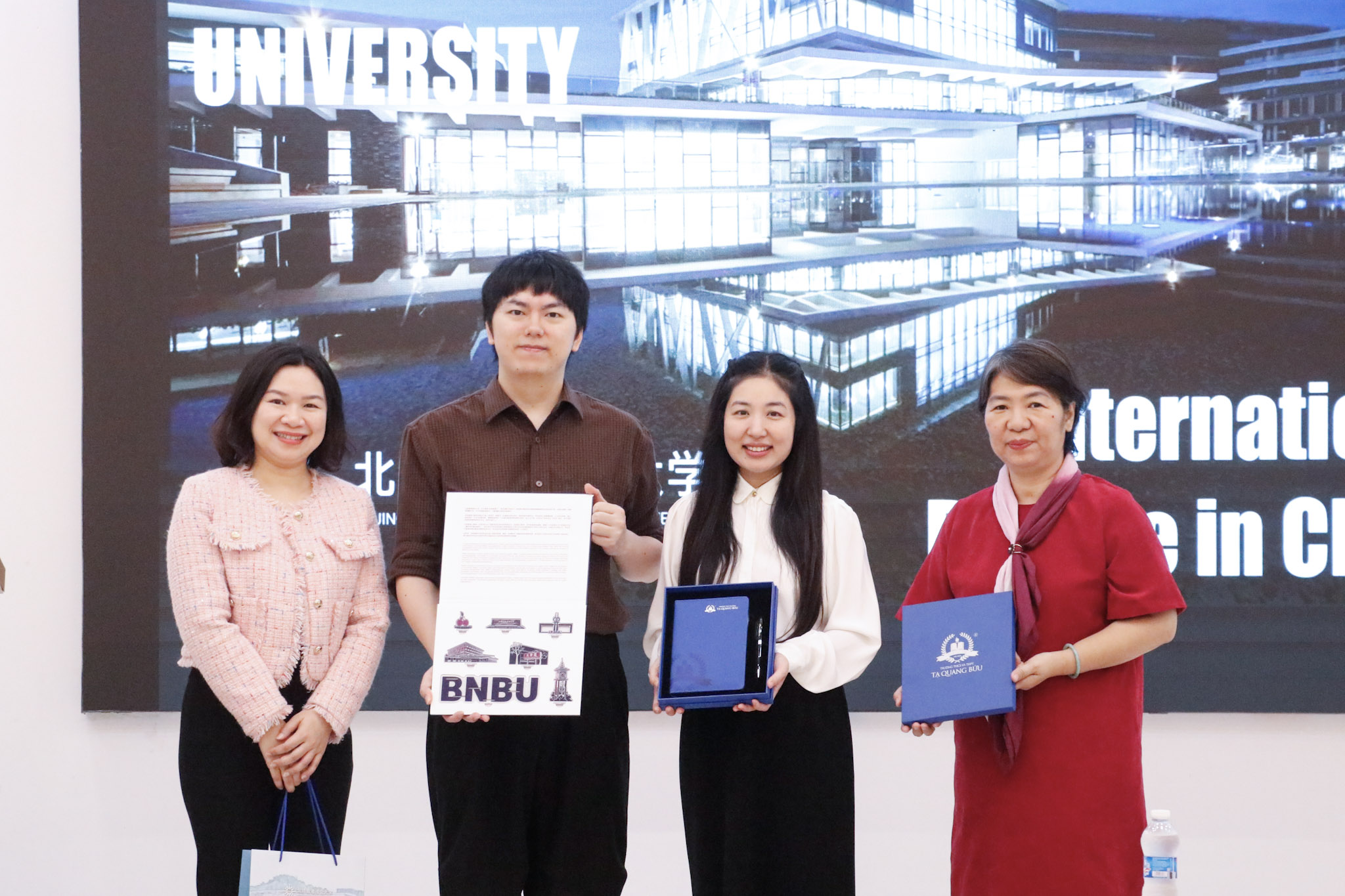 Cô Đào Thị Tươi (áo trắng), Phó Hiệu trưởng, trao quà lưu niệm tới ông Cody Meng - đại diện Beijing Normal - Hong Kong Baptist University (BNBU).