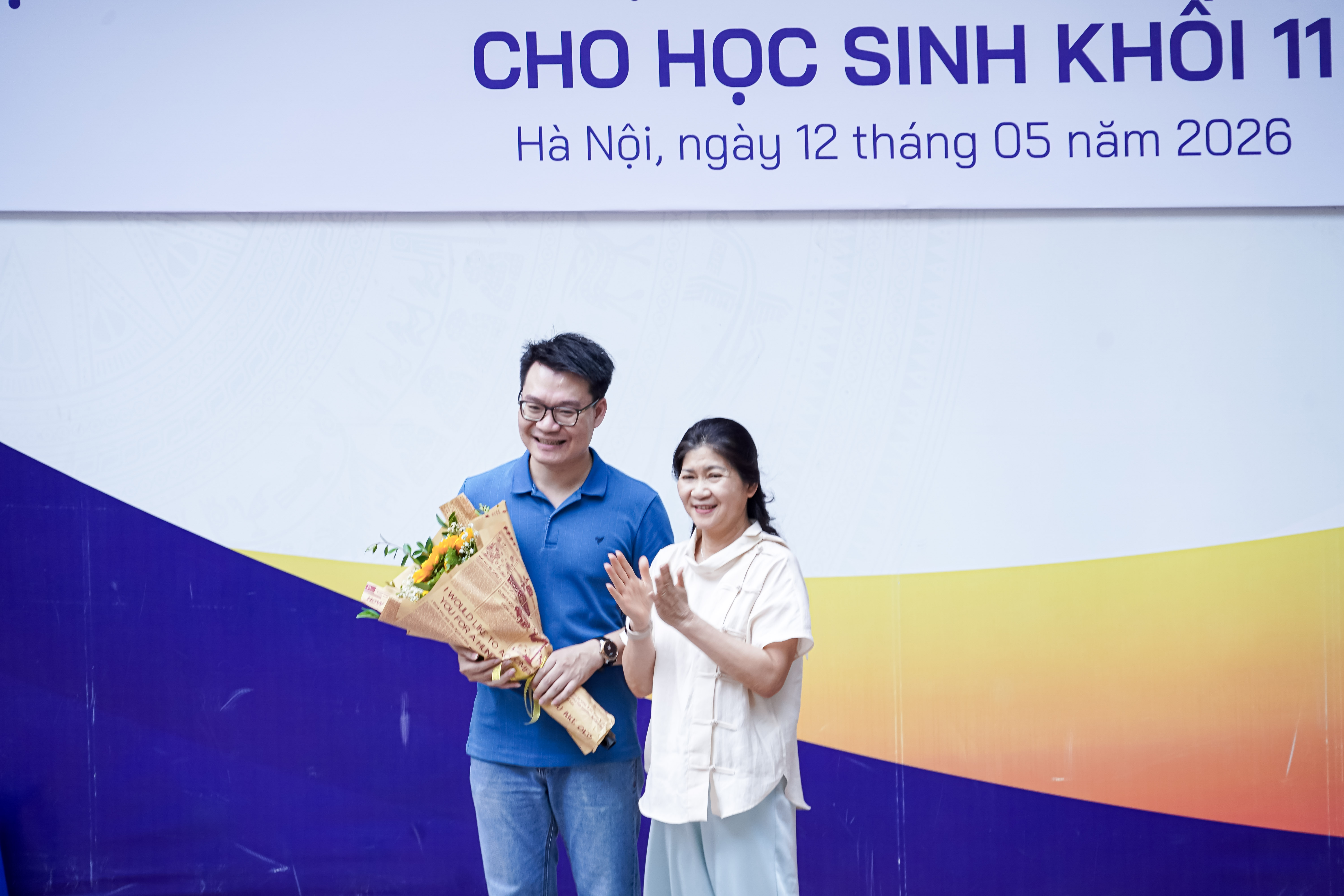 Cô Phạm Thị Xuân Hương - Hiệu trưởng Nhà trường tặng hoa thầy Vũ Khắc Ngọc.